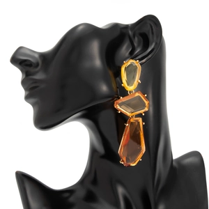 Detail of amber geometric resin drop earrings with gold metal claws on a black bust model