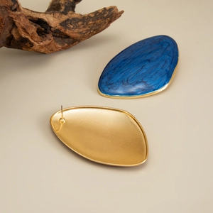 Detailed macro view of dark blue marble enamel earrings with polished gold metal edges