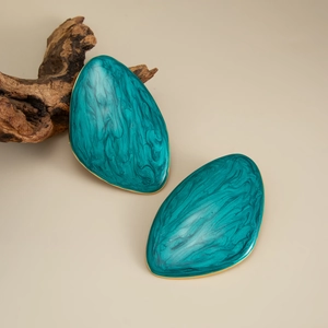 Macro detail of teal marble resin earring with gold metal edge on a natural wood branch