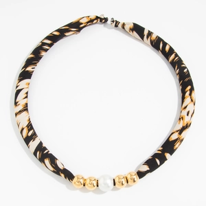 Detailopname van luipaardprint stoffen ketting met gouden kralen en grote parel
