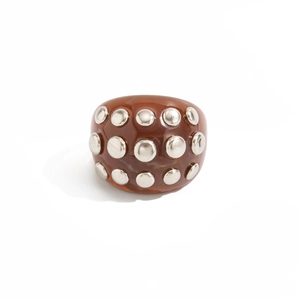 Macro view of vintage amber resin ring featuring decorative silver metal rivets and studs