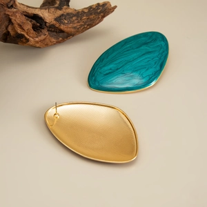 Macro detail of vintage oval earrings with teal enamel inlay and golden metal texture