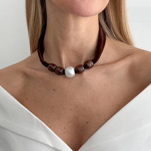 Detailed close-up of a brown velvet choker featuring wood beads and a large white pearl