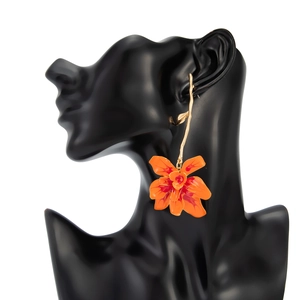 Detail of 3D orange orchid earring with red spots on black mannequin display