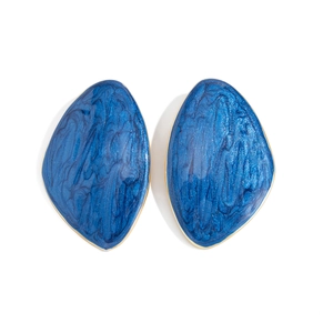 Macro detail of royal blue resin earrings with golden metal edges and sand texture