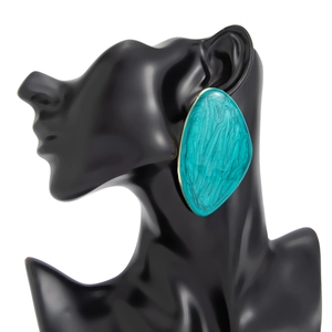 Detailed view of turquoise resin drop earring with gold trim on a black mannequin