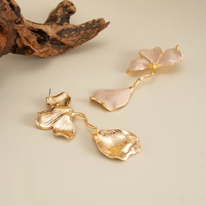 Détail de boucles d'oreilles asymétriques plaquées or avec pétales émaillés roses