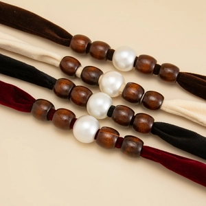 Close-up of velvet choker necklaces with textured wood beads and a central faux pearl