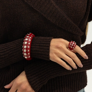 Retro red resin bangle and ring set with silver rivets on a knit sweater background