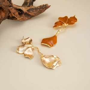 Détails de boucles d'oreilles fleurs en émail caramel avec pétales dorés et texture