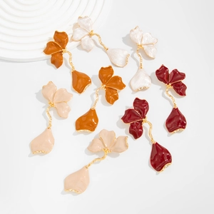 Détail de boucles d'oreilles florales pendantes en blanc, marron, nude et bordeaux