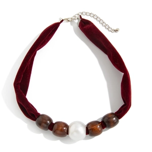 Close-up of burgundy velvet choker with dark wood beads and white imitation pearl detail