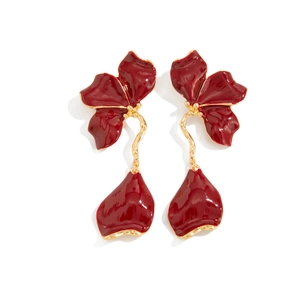 Detail showing long red enamel petal earrings with golden twist stems and floral accents