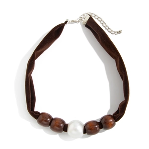 Detail of velvet choker with brown wood beads and a central white faux pearl accent