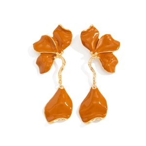 Détail de boucles d'oreilles fleurs orange caramel avec bord doré et finition émaillée