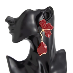 Detail of red floral earrings with enamel petals and gold metallic fringe on a model