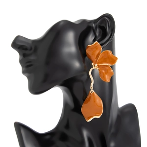 Détail de boucles d'oreilles 3D à fleurs orange caramel avec des pétales et métal doré