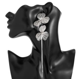 Détail de boucles d'oreilles fleurs argentées avec strass et longs glands sur modèle