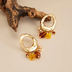 Dettaglio di orecchini vintage in oro con perle in resina e finitura in metallo martellato
