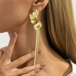 Gros plan de boucles d'oreilles pétales dorés avec longues chaînes serpent sur modèle