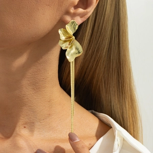 Vue détaillée des boucles d'oreilles fleurs dorées avec pétales et longs pompons