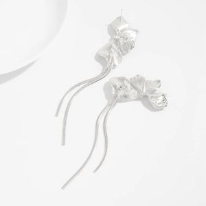 Détail de boucles d'oreilles fleur argentée avec pétales martelés et longues franges