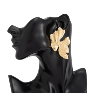 Macro-opname van goudkleurige sculpturale metalen oorbellen met abstracte bloembladen