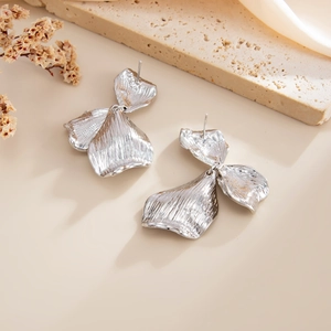Vue détaillée des boucles d'oreilles fleur argentée aux pétales ondulés et martelés