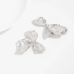 Vue détaillée de boucles d'oreilles en argent aux pétales 3D texturés et fini ondulé