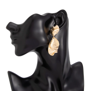 Détail de grandes boucles d'oreilles feuille de ginkgo dorées avec texture métal martelé