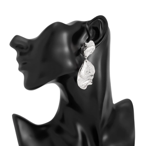 Détail de boucles d'oreilles pétales argentés à texture martelée sur modèle noir