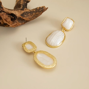Détail de boucles d'oreilles dorées texturées avec pendentifs en résine marbrée