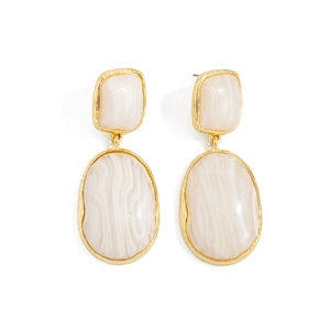Détail de boucles d'oreilles pendantes vintage dorées avec texture pierre marbre blanc