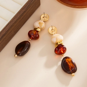 Gros plan de boucles d'oreilles en résine bohème avec textures marbre et ambre sur métal