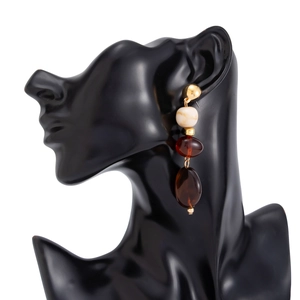 Gros plan de boucles d'oreilles pendantes en résine ambre sur un présentoir mannequin noir