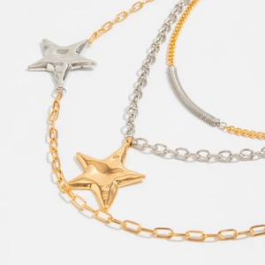 Macro detail of layered metallic star pendant necklaces with gold and silver finish