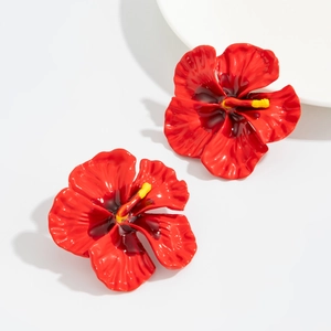 Detailed view of red enamel hibiscus earrings with golden stamen and metallic texture