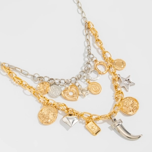 Detail view of multi-layered necklace with heart, star, and coin pendants in gold and silver