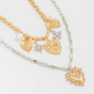Detail of layered gold and silver chains with heart, star, and pearl pendants