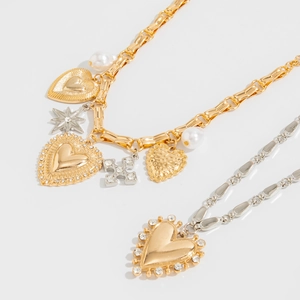 Detail of layered gold and silver necklaces with heart pendants and star charms on white