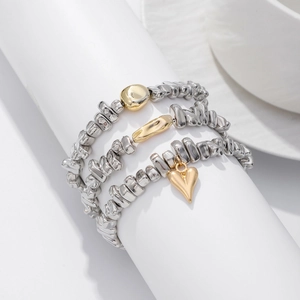 Detailaufnahme von 3-teiligen silbernen Perlenarmbändern mit goldenem Herzanhänger