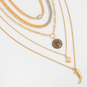 Detail of layered gold necklaces with Cuban links, embossed charms, and crystal pendants