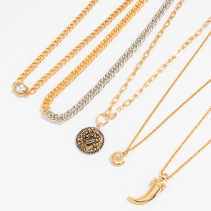 Detailed flat lay of layered gold and silver star, heart, and coin pendant necklaces