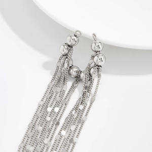 Détail de boucles d'oreilles à pampilles argentées avec chaînes et perles polies