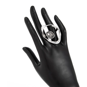 Vue macro détaillée d'une bague irrégulière en argent avec une pierre grise sur une main noire
