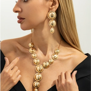 Dettaglio della collana con dischi d'oro lucido e orecchini a livelli su una modella