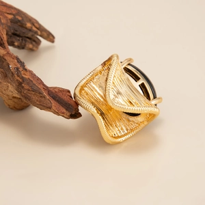 Detailed view of a vintage gold-toned ring with black oval stone and textured weaving