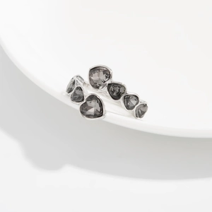 Dettaglio dell'anello aperto in argento con cristalli grigi a forma di cuore su ceramica
