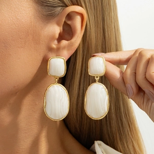 Close-up of geometric resin drop earrings with gold metal frame and marble texture