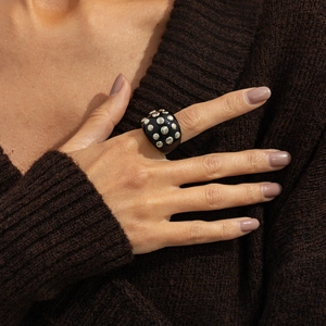 Close-up of black dome ring with silver stud accents on a knit background
